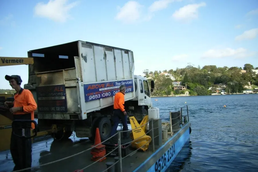 Above All truck loaded on a barge beside a waterfront home