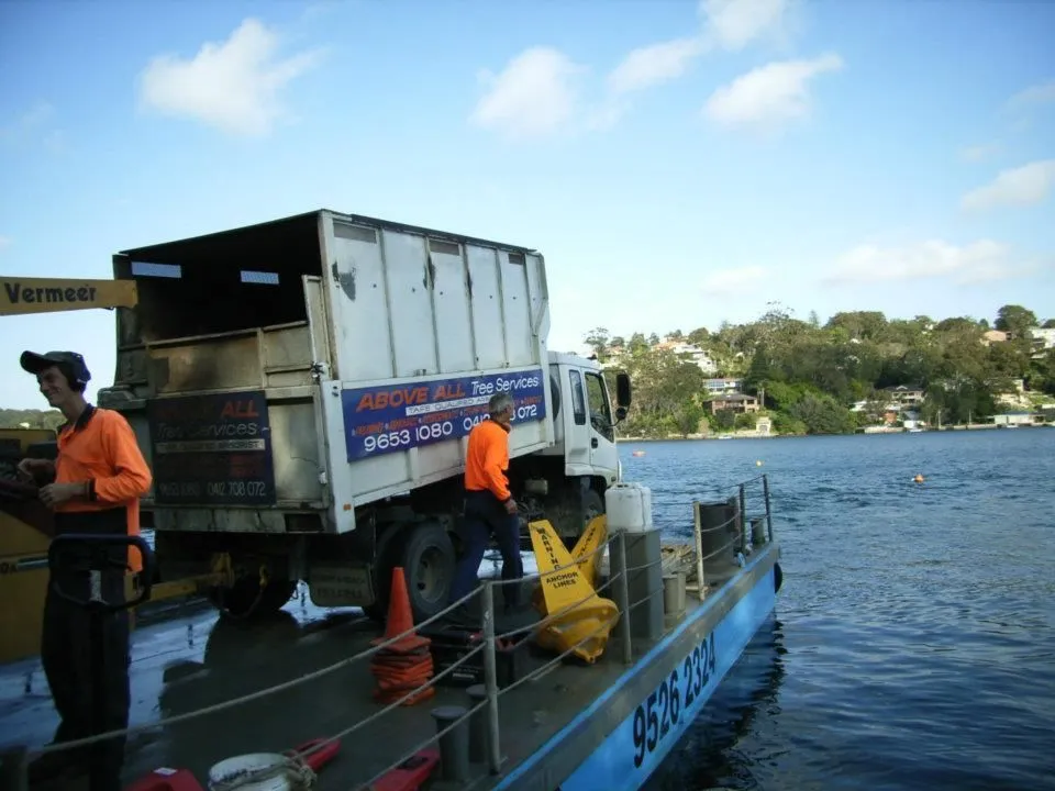 Above All truck loaded on a barge beside a waterfront home